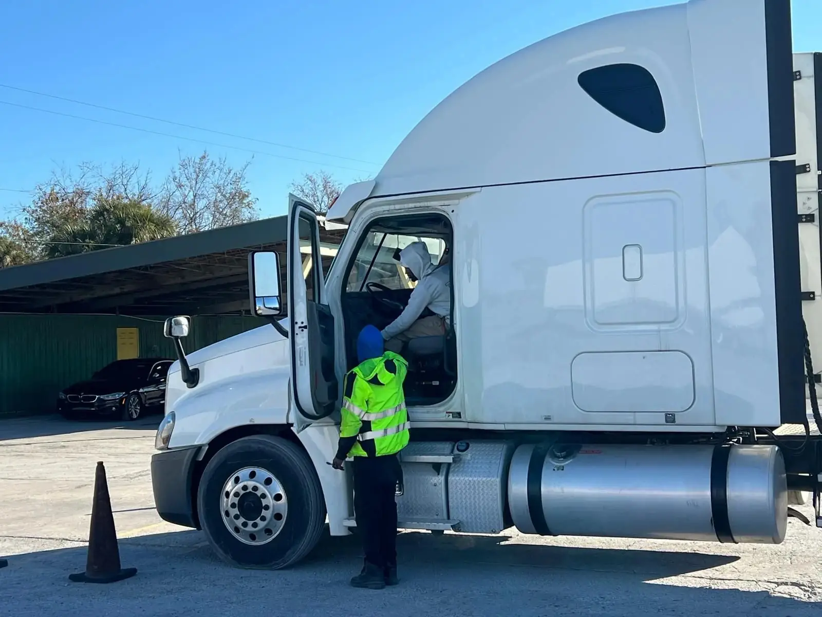 Instructor in a safety vest at the door of a white semi truck on the training yard